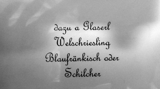 Hier ist ein Foto einer österreichischen Speisekarte zu sehen - eine Weinempfehlung. Zu lesen ist der Text "dazu a Glaserl Welschriesling Blaufränkisch oder Schilcher"